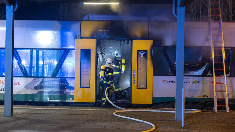 Feuerwehrleute gehen unter Atemschutz in den Zug und löschen den Brand.