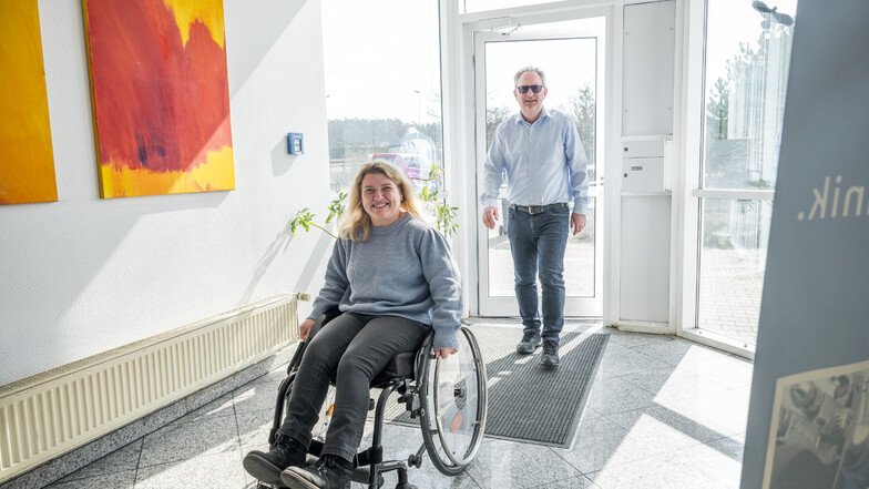 Eva Lenz (l) kommt zusammen mit Andreas Bräuer (r), Assistent der Geschäftsführung, in das Gebäude der ReiColor Chemie-GmbH. Sie ist gehbehindert und auf ihre Gehhilfe oder ihren Rollstuhl angewiesen.