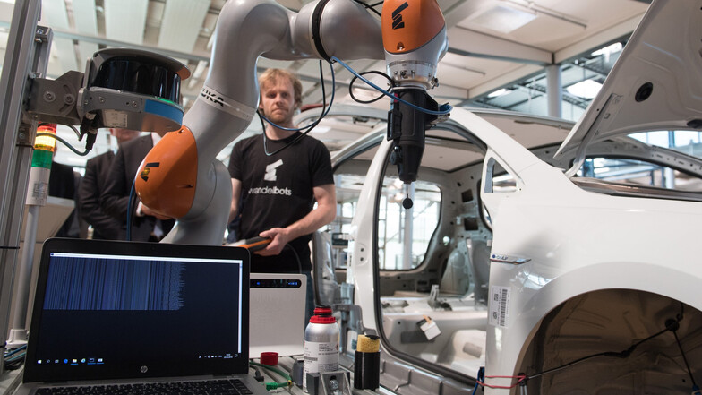 Sebastian Werner, Gründungsmitglied des Dresdner Start-up Wandelbots, steuert in der Gläsernen Manufaktur von VW an einem e-Golf einen Primerpinsel, der eine Grundierung zur Oberflächenvorbereitung aufträgt.
