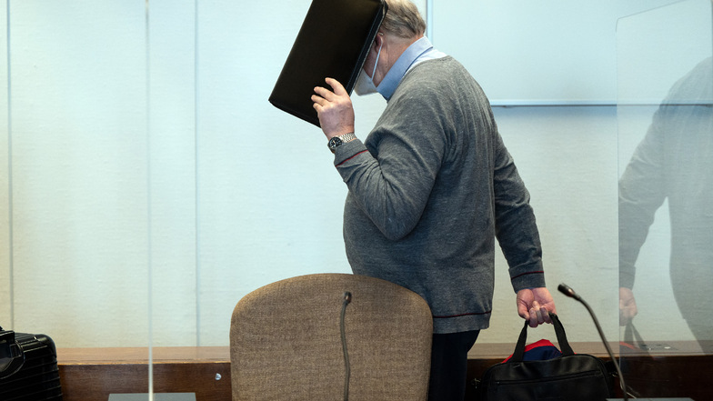Der angeklagte katholische Priester hält sich im Gerichtssaal eine Mappe vor das Gesicht.