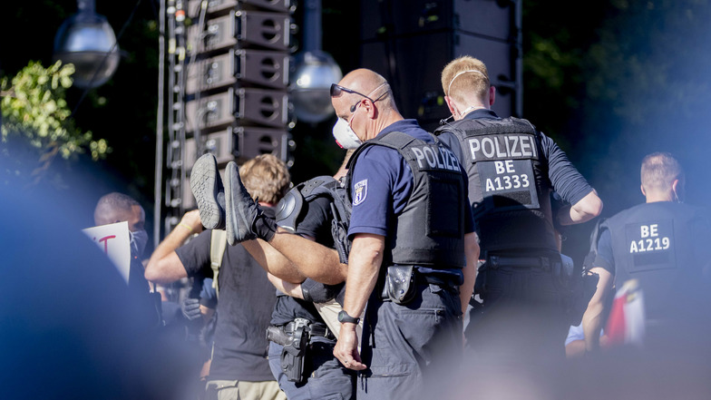 Polizisten tragen bei der Kundgebung gegen die Corona-Beschränkungen eine Person von der Bühne. Die Polizei hatte die Veranstaltung aufgelöst.