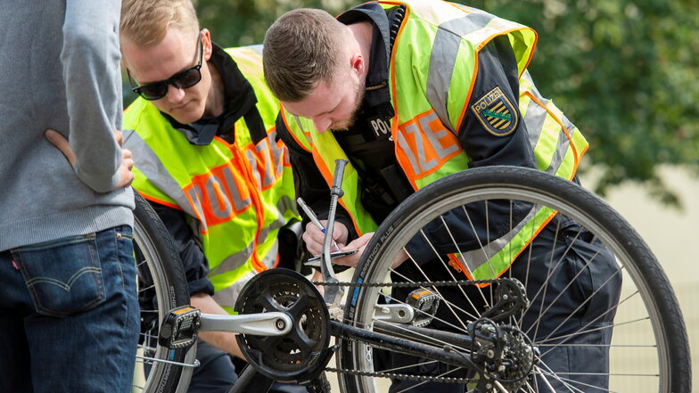 Polizisten schauen auf der Suche nach geklauten Rädern bei einer Kontrolle auf die Rahmennummer.