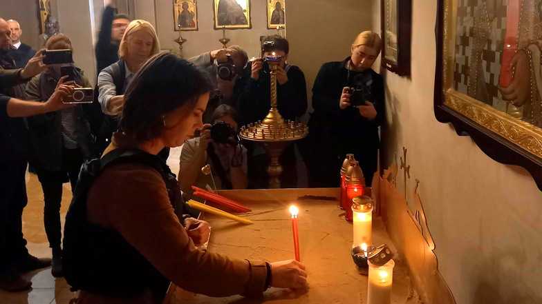 Baerbock (M, Bündnis 90/Grüne) entzündet eine Kerze für die Opfer in einer Kirche in Butscha.