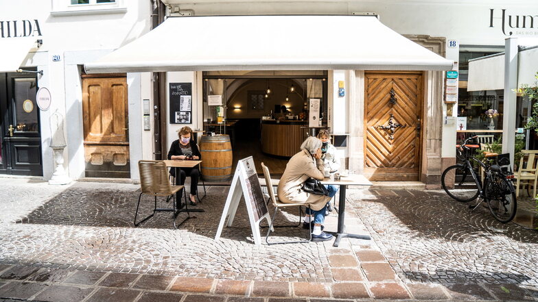 Frauen mit Mundschutz trinken Kaffee vor einer Bar im norditalienischen Bozen.