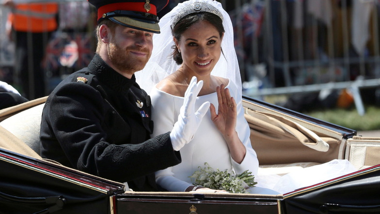 19.05.2018: Bräutigam Prinz Harry und seine Braut Herzogin Meghan fahren nach ihrer Hochzeit in einer Kutsche und winken Menschen zu, die den Straßenrand säumen.