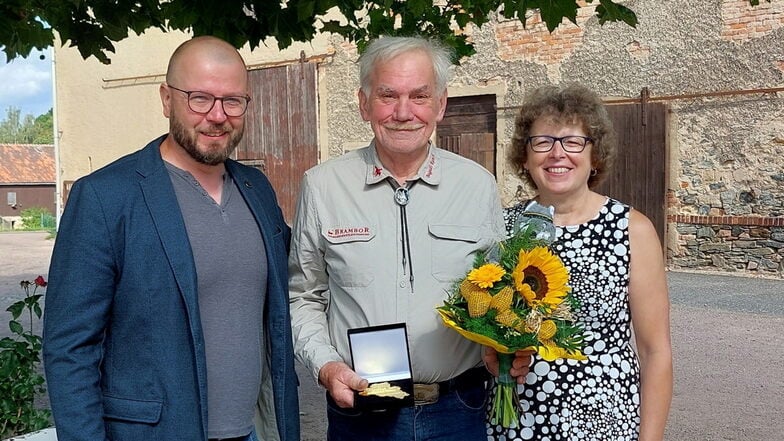 KSB-Geschäftsführer Benjamin Kahlert (li.) hat Klaus Bernhard aus Seifersdorf mit der Ehrenplakette des Sportbundes geehrt. Seine Frau Claudia freut sich mit ihm.