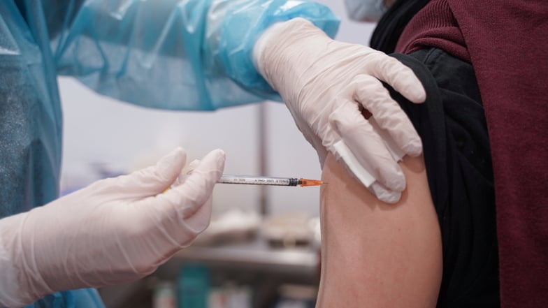 Ein junger Mann erhält eine Booster-Dosis eines Corona-Impfstoffs. Jetzt gibt es auch in Sachsen die neuen auf Omikron angepassten Impfstoffe. Die Inzidenz im Landkreis Meißen fällt wieder.
