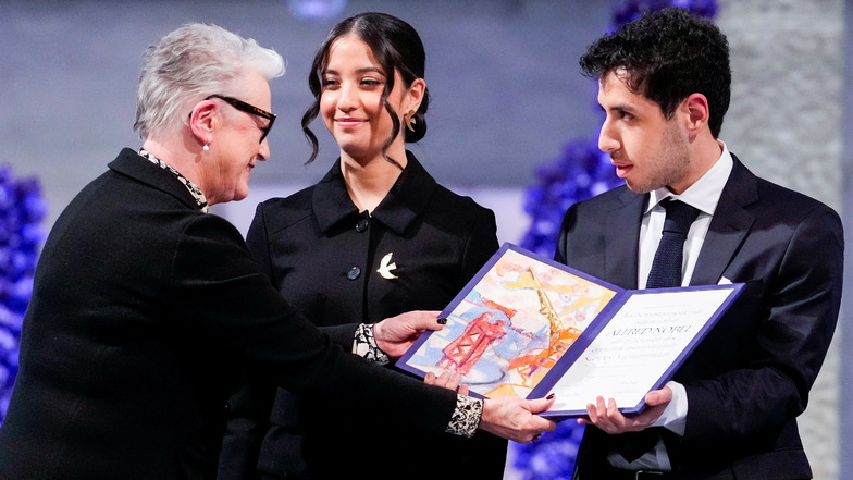 Berit Reiss-Andersen (l) überreicht Ali und Kiana Rahmani die Urkunde während der Verleihung des Friedensnobelpreises 2023 im Rathaus von Oslo. Sie nahmen den Friedensnobelpreis stellvertretend für ihre Mutter Mohammadi  entgegen, die im Iran inhaftiert i