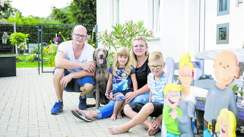 Oliver und Julia Kupke sitzen mit ihren Kindern Arthur und Lore vor ihrem Haus in Jauernick-Buschbach. Mit dem Hausbau hat sich die Familie einen Lebenstraum erfüllt. Das Glück perfekt macht seit ein paar Wochen ein neues Familienmitglied: Hund Hans.