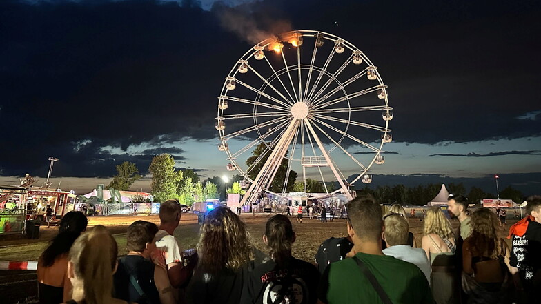 Besucher des Highfield-Festivals blicken am vergangenen Samstag auf ein Riesenrad, an dem Flammen zu sehen sind.