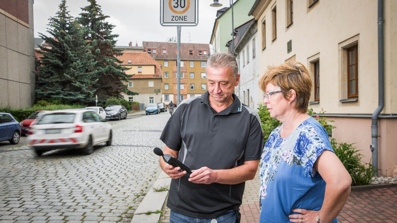 Anwohner protestieren gegen den Straßenlärm und die schlechte Fahrbahn auf der Stolpener Straße in Radeberg. Andreas Krohn hat ein Lärmmessgerät mitgebracht. Carola Nietzsche sieht sich das Ergebnis an. Mehr als 80 Dezibel werden angezeigt.