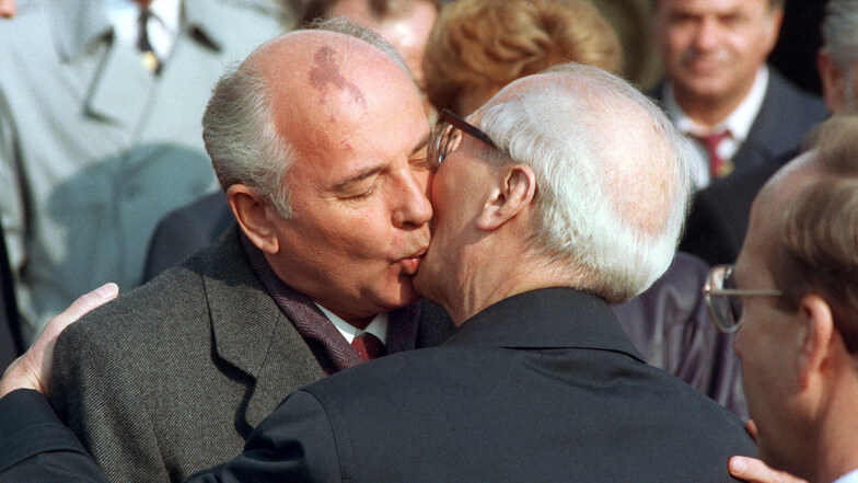 Michail Gorbatschow (l) wird nach seiner Ankunft zu den Feierlichkeiten zum 40-jährigen Staatsjubiläum der DDR von Erich Honecker mit dem traditionellen Bruderkuss willkommen geheißen.