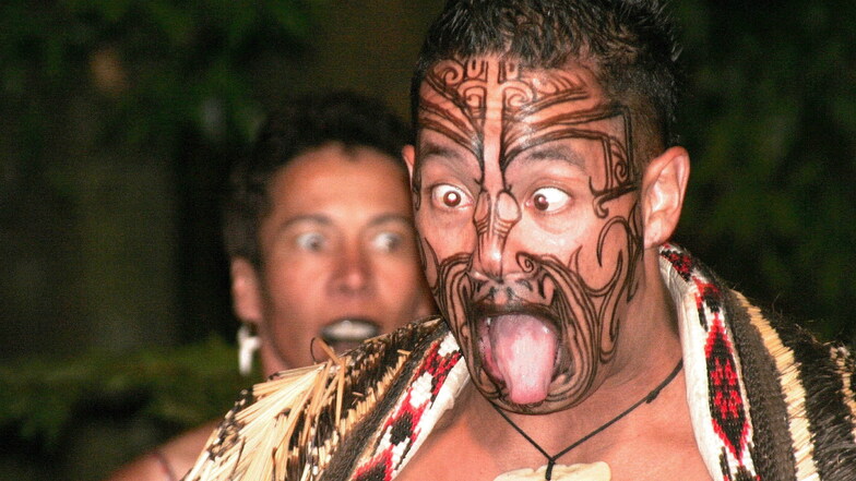 Maori-Show im nächtlichen Wald:  Krieger tauchen unvermittelt aus der dunkler Nacht auf und ihre Gesichtstätowierungen und Zungen .