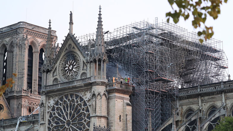 16.04.2019, Frankreich, Paris: Feuerwehrleute stehen nach einem Brand neben einem Baugerüst auf der Kathedrale Notre-Dame. Bei dem verheerenden Brand der Pariser Kathedrale Notre-Dame war die Feuerwehr in großer Sorge um die beiden Türme des massiven Baus