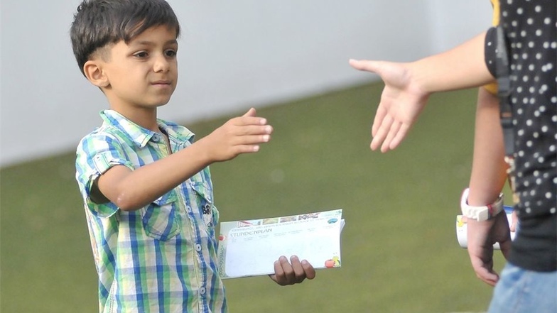 Sinnbildliche Geste in der Meißner Arche. Nach einem Fußballturnier für die Kinder reicht dieser Junge einer Betreuerin die Hand.
