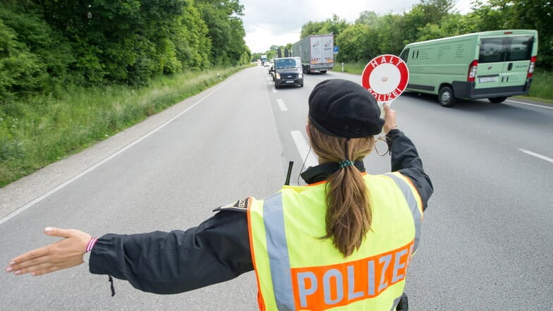 Eine Polizistin winkt an einer Kontrollstelle der bayerischen Landespolizei nahe der österreichischen Grenze ein Fahrzeug auf einen Parkplatz, um Schleusungen zu entdecken.