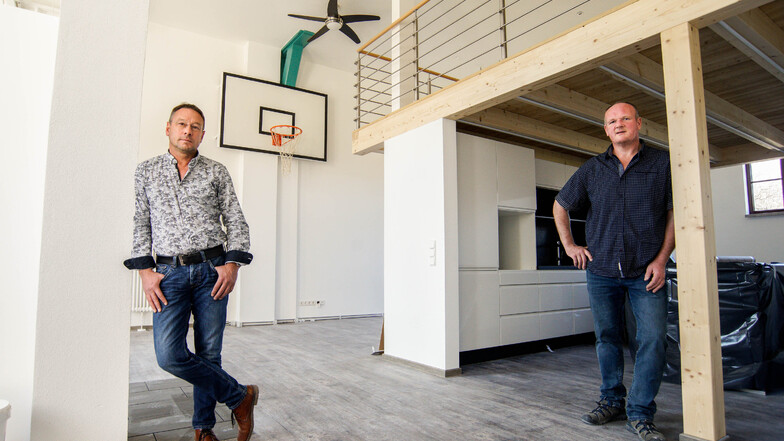 Die Bauherren Andreas Bascha (links) und Edgar Lehmann stehen in einer der neuen Wohnungen, die sie in Neukirch in einer ehemaligen Turnhalle geschaffen haben. Sportgeräte wie der Basketballkorb wurden erhalten.