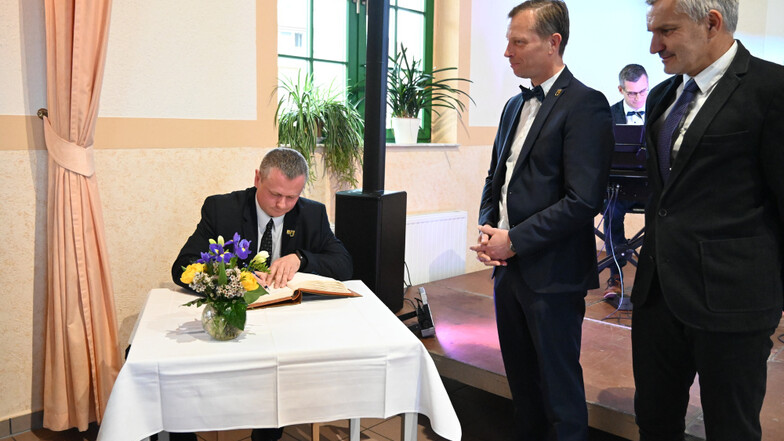 Bürgermeister Marek Chrabazcz trägt sich hier ins Goldene Buch der Stadt Wittichenau ein, die Amtskollegen Markus Posch und Vladimir Vyhnálek schauen zu.