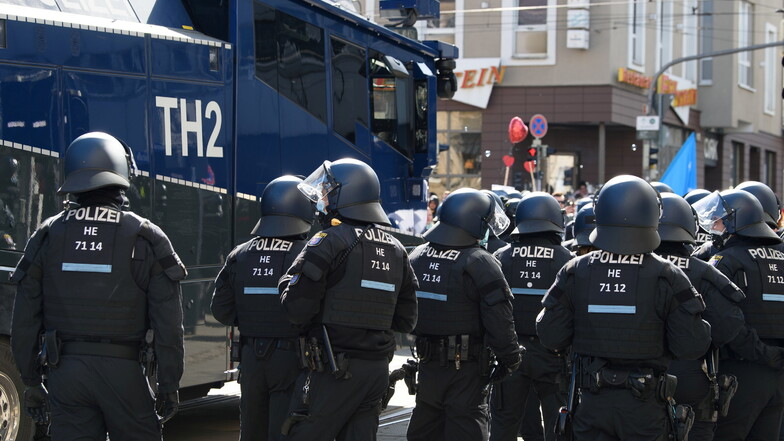 Einsatzkräfte der Polizei stehen in Kassel neben einem Wasserwerfer.