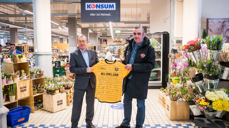 Dynamos Sport-Geschäftsführer Ralf Minge (r.) zeigt gemeinsam mit Vorstandssprecher Roger Ulke vom Konsum eines der 200 Trikots.