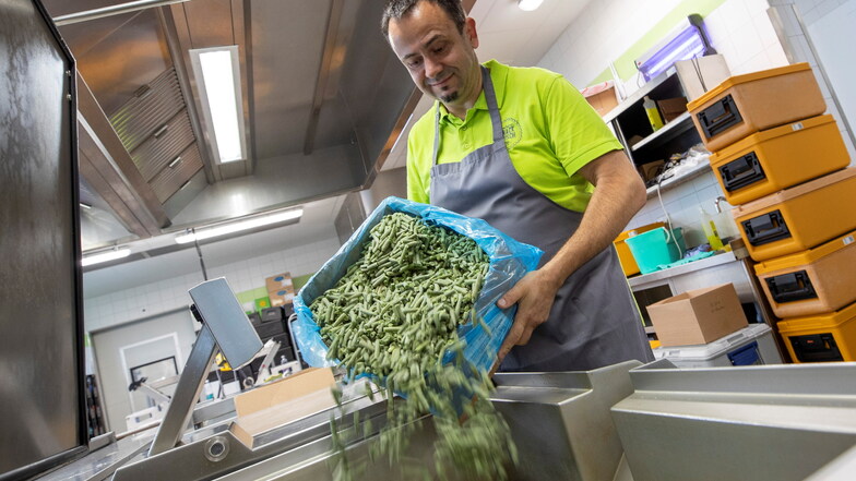 Über 3.000 Portionen täglich: "Knack Frisch"-Küchenleiter Nino Stagge schüttet am neuen Arbeitsplatz Bohnen in einen Kochbehälter.