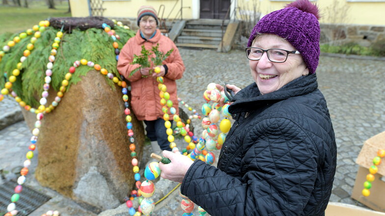 Karin Beyer und Helma Schoft (r.) haben begonnen, den Osterstein vor dem Gemeindeamt in Schönau-Berzdorf zu schmücken.