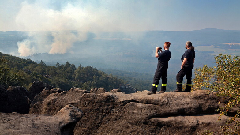 Kai Bigge (rechts), Wehrleiter der Freiwilligen Feuerwehr Bad Schandau und Richard Rittner beobachten den Brand am Montag vom Großen Winterberg aus. Inzwischen soll es auch hier brennen.