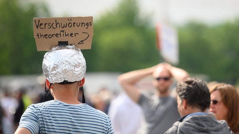Dieser Mann trägt während einer Protestkundgebung in Stuttgart einen Aluhut mit einem Schild, auf dem "Verschwörungstheoretiker" steht.