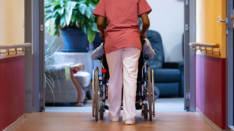Eine Bewohnerin eines Pflegeheims wird von einer Pflegerin einen Gang entlang geschoben.
