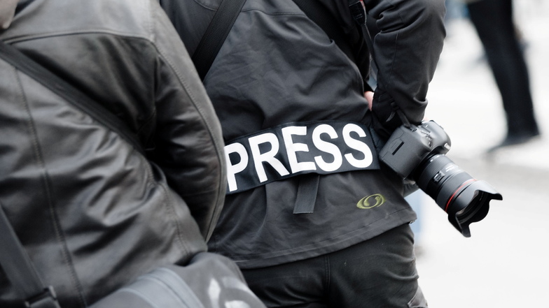 Ein Fotoreporter trägt auf einer Demonstration einen Aufnäher mit dem Text "PRESS" auf seiner Jacke, um sich gegenüber Polizei und Demonstranten als Journalist zu kennzeichnen.