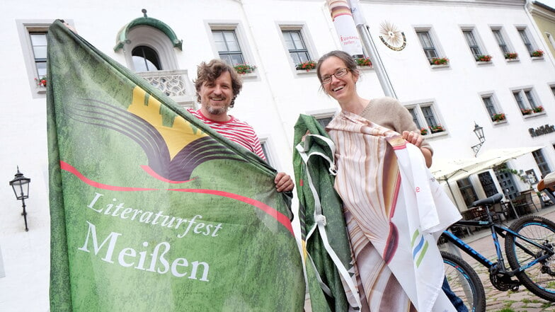 Daniel Bahrmann und Maria Fagerlund haben Spaß beim Aufhängen der Literaturfest-Fahnen auf dem Meißner Markt.