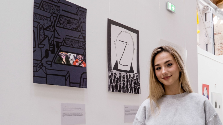 Alina Nesterenko steht in der Ausstellung mit Bildern, die von ukrainischen Jugendlichen gemalt worden sind.
