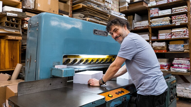 Arnd Melzer arbeitet bei Augusta-Druck in Görlitz an der Schneidemaschine. In den Regalen stapeln sich die verschiedensten Papierarten für unterschiedlichste Druckaufträge.