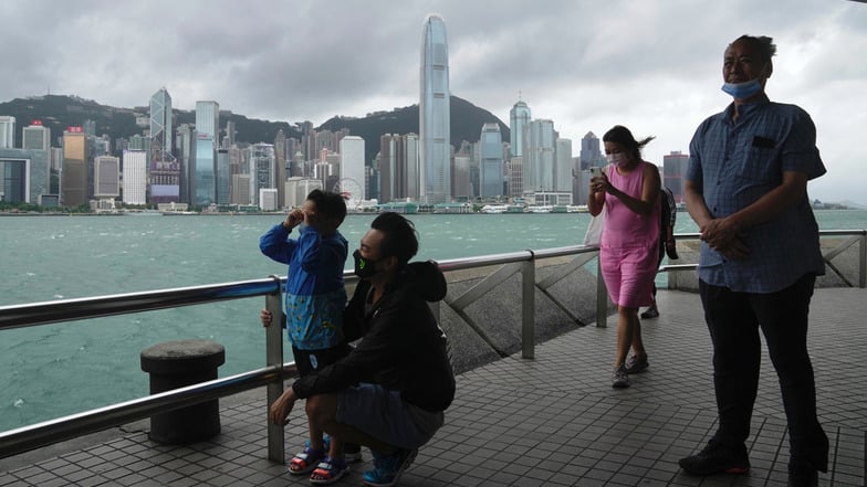 Hongkong: Menschen gehen bei stürmischem Wetter am Ufer entlang. Hongkong beendet die Quarantänepflicht für einreisende Menschen.