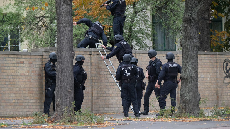 Polizisten überwinden eine Mauer an der Hallenser Synagoge.