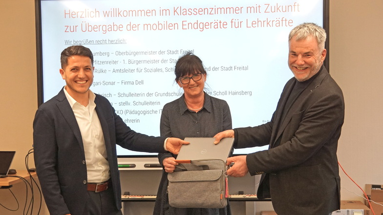 Oberbürgermeister Uwe Rumberg (r.) und Isa Begari-Sonar (l.) von der Firma Dell bei der Übergabe eines Laptops an Schulleiterin Sybille Behrisch.