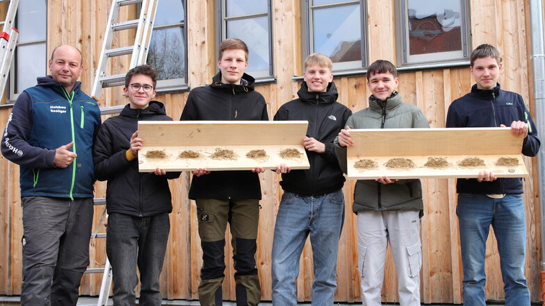 Handwerksmeister Maik Seeliger und das Schülerteam der Zinzendorfschulen mit den selbst gefertigten Schwalbenbrettern für die Turnhalle.