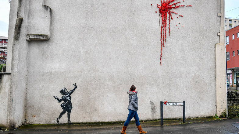 Das neue Banksy-Werk in Bristol: Zu sehen ist ein Mädchen, das mit einer Steinschleuder in der Hand Richtung eines riesigen Kleckses aus roten Rosen zielt.