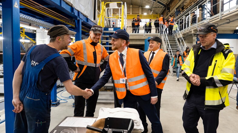 Ministerpräsident Michael Kretschmer (Mitte) gratuliert einem Alstom-Mitarbeiter zum Auftrag für die Straßenbahn-Rohbauten, rechts neben Kretschmer stehen OB Octavian Ursu und Alstom-Werksleiter Jens Koep.