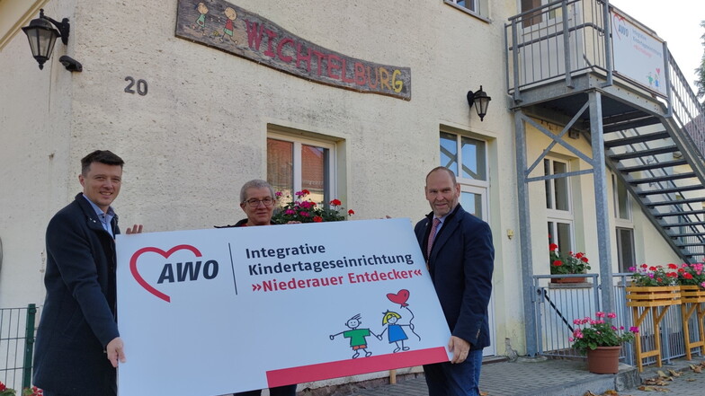Die Kita trägt jetzt den Titel "Niederauer Entdecker": Bürgermeister Markus Renner und Claudia Grüneberg, Geschäftsführerin der AWO Kinder- und Jugendhilfe, und der Niederauer Bürgermeister Steffen Sang vor dem neuen Schild.