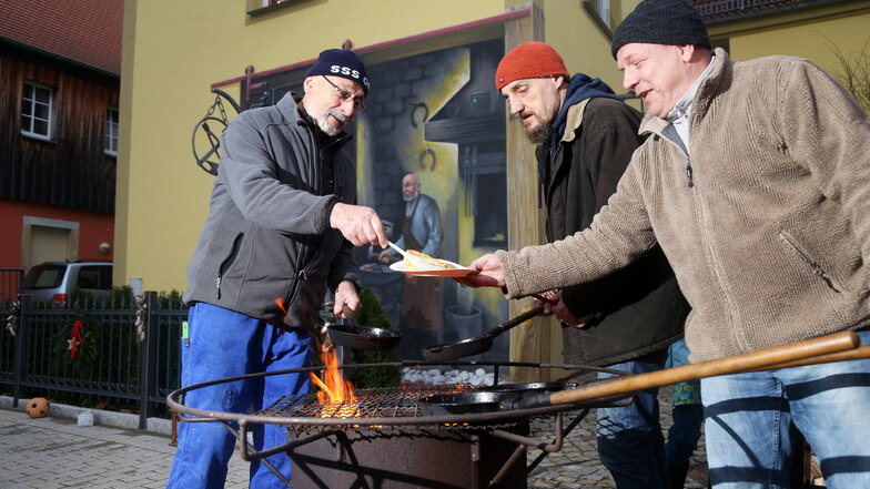 Schmied Werner Richter (links) und Michael Rudolph braten in Gröba leckere Plinsen über dem Holzfeuer.