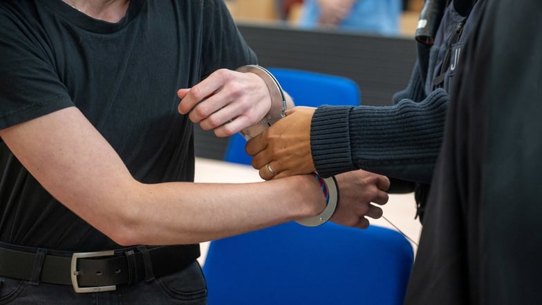 Eine Justizbedienstete entfernt vor der Urteilsverkündung die Handschellen an der wegen unterlassener Hilfeleistung angeklagten Ex-Freundin des Arztes.