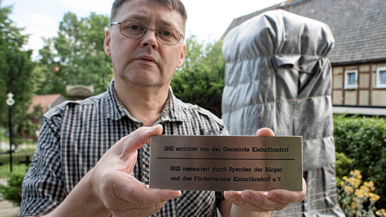 Ralf Granzow zeigt die Tafel, die dokumentiert, dass der Förderverein Kleinröhrsdorf das Kriegerdenkmal mit Spendengeldern restaurieren ließ.