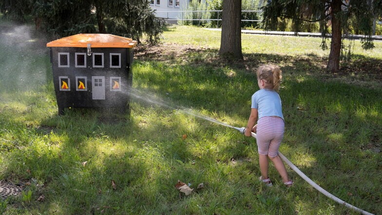 Und eine kleine Feuerwehrfrau: Dieses Mädchen löscht ein Spielzeughaus mit dem Feuerwehrschlauch.