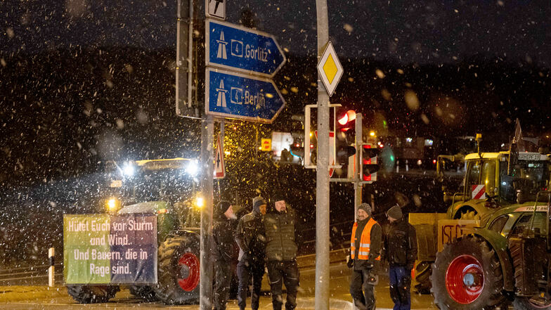 Landwirte blockieren mit ihren Traktoren die Autobahnauffahrt Dresden Wilder Mann. Links ist ein Schild mit der Aufschrift "Hütet euch vor Sturm und Wind und Bauern, die in Rage sind" angebracht.