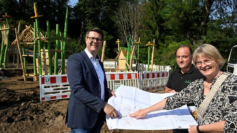 Oberbürgermeister Sven Liebhauser (von links), LFT-Geschäftsführer Christian Fischer und Maja Köhler vom Planungsamt der Stadt stehen vor dem Spielplatz, der seit dieser Woche im Bürgergarten aufgebaut wird.