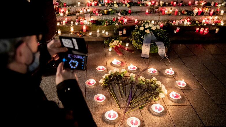 Ein Mann fotografiert bei der Gedenkfeier 2020 am vierten Jahrestag des Anschlags auf den Weihnachtsmarkt am Breitscheidplatz das Mahnmal "Goldener Riss", an dem viele Kerzen niedergelegt wurden, darunter auch Kerzen und weiße Rosen in Form eines Herzens.