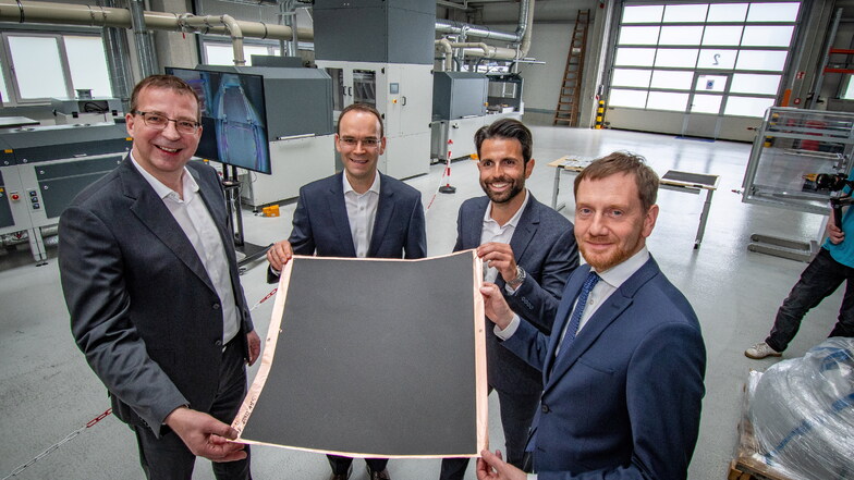 Das ist der Kern der Innovation: Holger Gritzka (von links), Danny Weckwarth und Serhat Yilmaz von Blackstone Technology und der sächsische Ministerpräsident Michael Kretschmer zeigen die gedruckten Anoden für Lithium-Ionen Batterien.