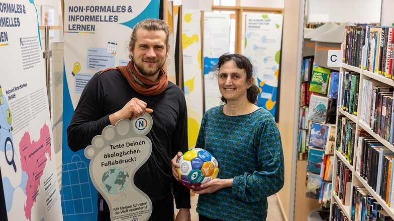 Lukas Vogt und Jana Petzold bereiten die Ausstellung "Bildung für nachhaltige Entwicklung" in der Stadtbibliothek Freital vor.