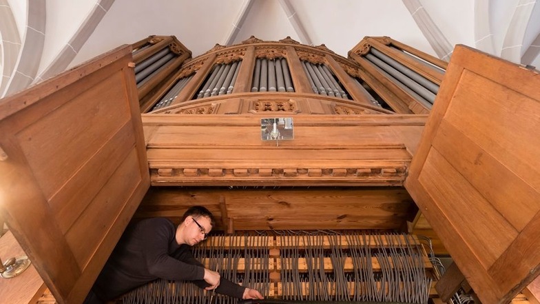 Orgelbauergeselle Lukas Bartsch hockt in der Orgel.